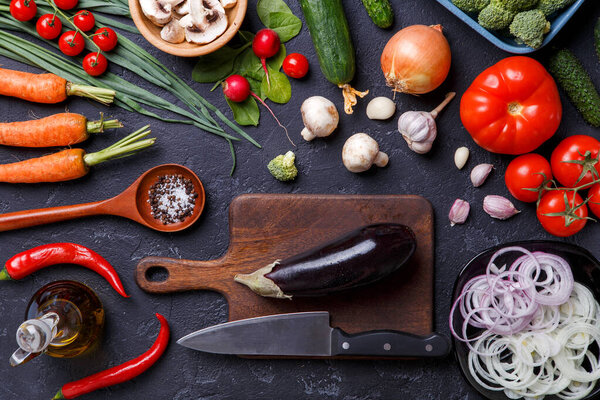 Изображение поверх свежих овощей, шампанского, разделочной доски, масла, ножа, баклажанов на столе
