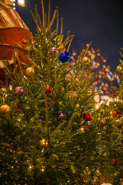 挂满金球 蓝球和红球的圣诞树在燃烧着的花环的模糊建筑背景上的照片 — 图库照片