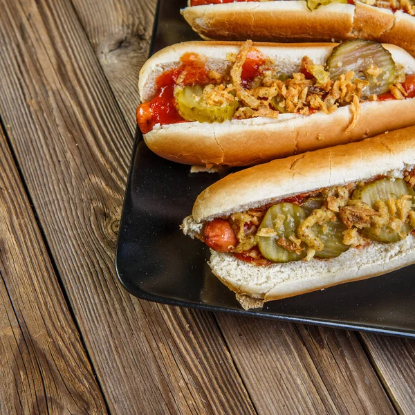 American hot dog with pickles,onions, ketchup and mustard on wood background