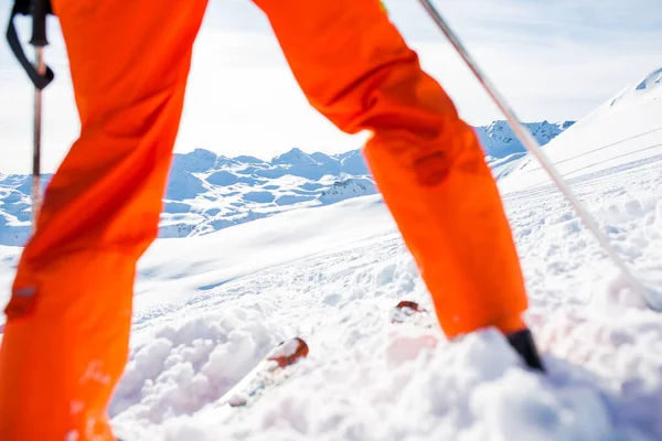 形象滑雪者的腿在橙色裤子 滑雪杆在冬季轨道上的白天 — 图库照片