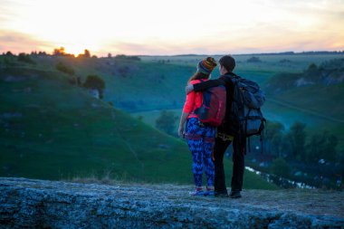 Gün batımında dağda iki turisti kucaklarken çekilmiş bir fotoğraf.