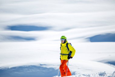 Gün boyunca karlı dağların arka planında kayak yapan sporcu adamın fotoğrafı