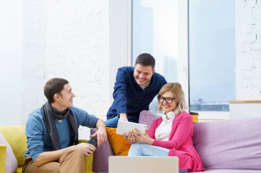 Arkadaş sohbet ve kullanarak bir smartphone, masaüstü bilgisayar, dizüstü bilgisayar koltukta otur. Sosyal medya kavramı.