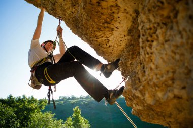 Kasklı turist kayalıklara tırmanıyor..