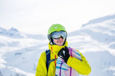 Kışın dağların arka planında snowboard yapan sporcu adamın fotoğrafı.