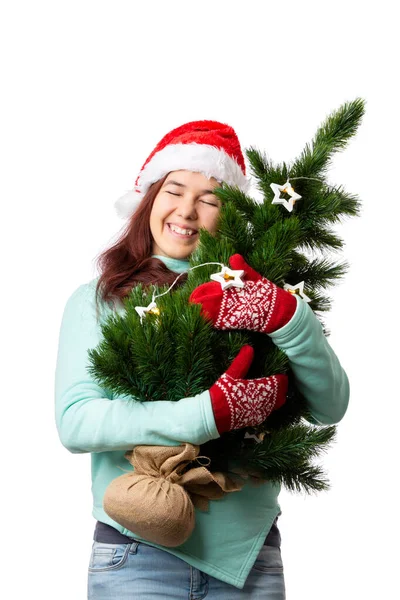 照片上的女人戴着圣诞老人的帽子 手上拿着圣诞树 白色的背景是空的 — 图库照片