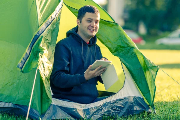 Hombre Está Sentado Una Tienda Con Una Tableta Zona Acampada —  Fotos de Stock