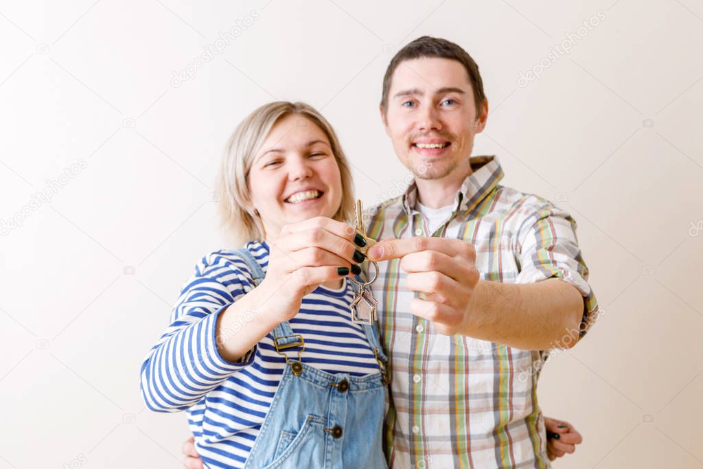Image of woman and man with keys from apartment against blank wall in apartment