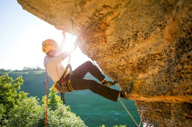 Tepeye tırmanan miğferli bir adamın görüntüsü. Güneş ışığı etkisi.