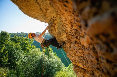 Kasklı turist kayalıklara tırmanıyor..