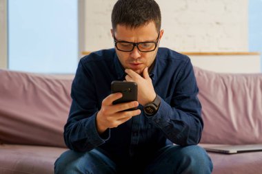 Adam kanepede ve smartphone kullanarak otur. Sosyal medya kavramı.