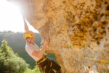 Miğferli turist yaz günü dağa tırmanıyor.