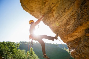 Tepeye tırmanan miğferli bir adamın görüntüsü. Güneş ışığı etkisi.