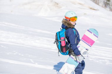 Kışın parkta sırt çantalı ve snowboard 'lu kadın sporcu görüntüsü