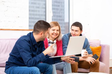 Arkadaş sohbet ve kullanarak bir smartphone, masaüstü bilgisayar, dizüstü bilgisayar koltukta otur. Sosyal medya kavramı.