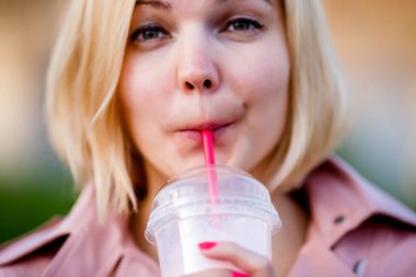 Parkta milkshake içen kadının portresi, bulanık arka plan