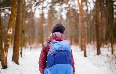 Öğleden sonra sırtında sırt çantası olan yürüyen bir kadının görüntüsü.