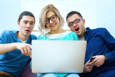 Arkadaş sohbet ve kullanarak bir smartphone, masaüstü bilgisayar, dizüstü bilgisayar koltukta otur. Sosyal medya kavramı.