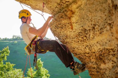 Miğferli bir turistin yaz günü dağa tırmandığı resim.