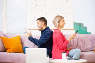 Arkadaşlar kanepede oturup sohbet eder ve akıllı telefon, masaüstü bilgisayarı kullanır. Sosyal medya kavramı.