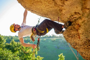 Miğferli bir turistin yaz günü dağa tırmandığı resim.