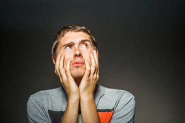 Boş siyah arka planda elleri çenesinde tişörtlü bir adamın fotoğrafı.