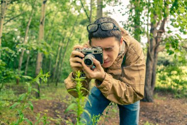 Gözlüklü bir biyolog yaz ormanında bitki yetiştiriyor.