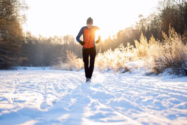 Sabah itibariyle kış ormandaki ağaçlar arasında çalışan sporcunun fotoğraf