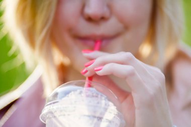 Sarışın, sokaktan kokteyl içiyor.