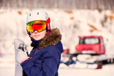 Bulanık kar günü arka planında maske ve kask takmış kadın sporcunun portresi. Renkli fotoğraf