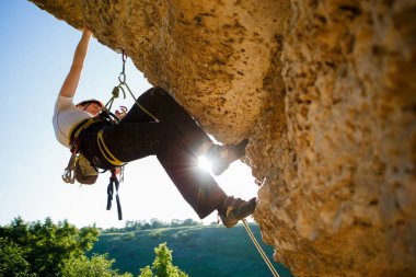 Kasklı turist kayalıklara tırmanıyor..