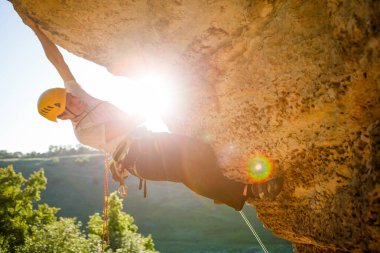 Tepeye tırmanan miğferli bir adamın görüntüsü. Güneş ışığı etkisi.