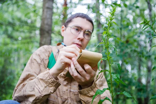 Bild Manlig Biolog Glas Med Penna Anteckningsbok Skogen Bland Växter — Stockfoto