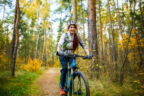 Photo of girl in helmet riding on bike in autumn forest