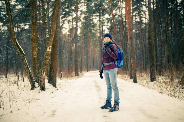 Öğleden sonra ormanda sırt çantalı, şapkalı, gülümseyen bir kadın fotoğrafı.