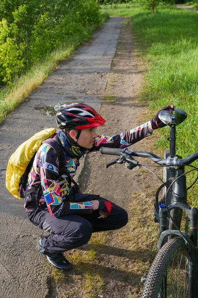 Zdjęcie Rowerzysty Noszącego Hełm Obok Roweru Drodze Lesie Ciągu Dnia — Zdjęcie stockowe