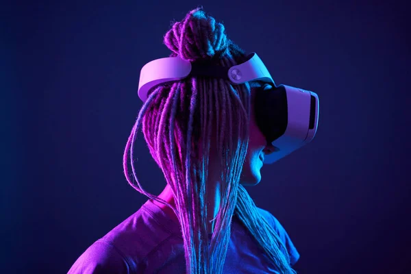 Woman is using virtual reality headset. Neon light studio portrait.