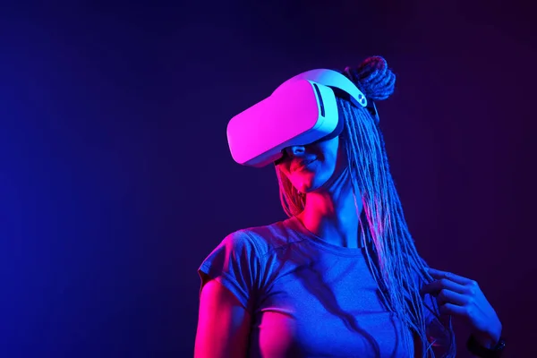 La femme utilise un casque de réalité virtuelle. Portrait studio lumière néon. — Photo