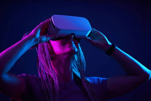 Frau benutzt Virtual-Reality-Headset. Neonlicht-Studioporträt. — Stockfoto