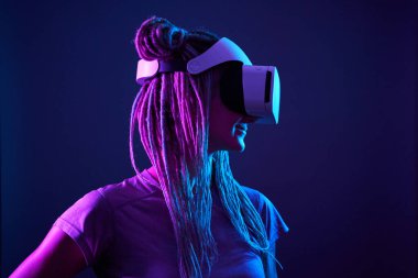 Kadın sanal gerçeklik kulaklığı kullanıyor. Neon Light Stüdyo Portresi.