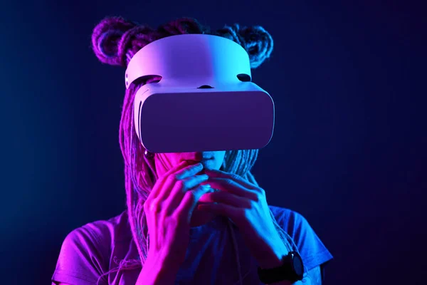 La mujer está usando auriculares de realidad virtual. Retrato de estudio de luz de neón. — Foto de Stock