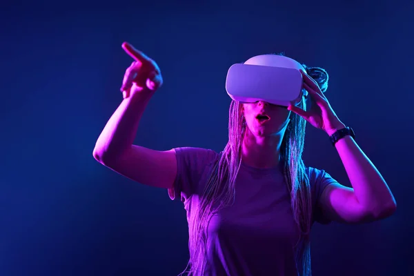 Donna sta usando cuffie realtà virtuale. Neon luce studio ritratto. — Foto Stock