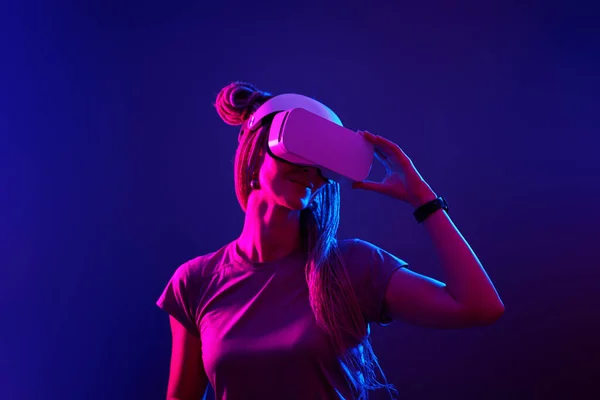 A mulher está usando fones de ouvido de realidade virtual. Retrato de estúdio luz néon. — Fotografia de Stock