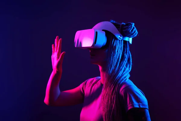 Frau benutzt Virtual-Reality-Headset. Neonlicht-Studioporträt. — Stockfoto