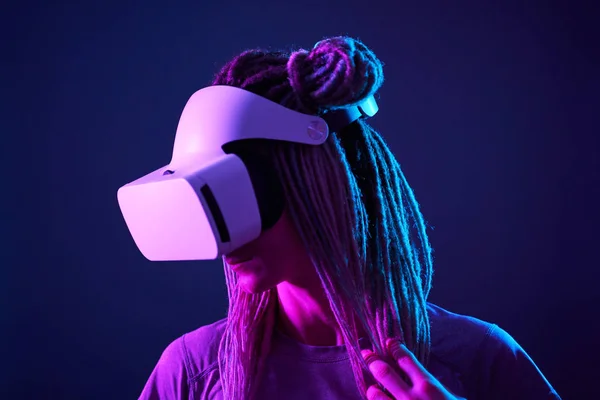 Vrouw gebruikt virtual reality headset. Neon licht studio portret. — Stockfoto