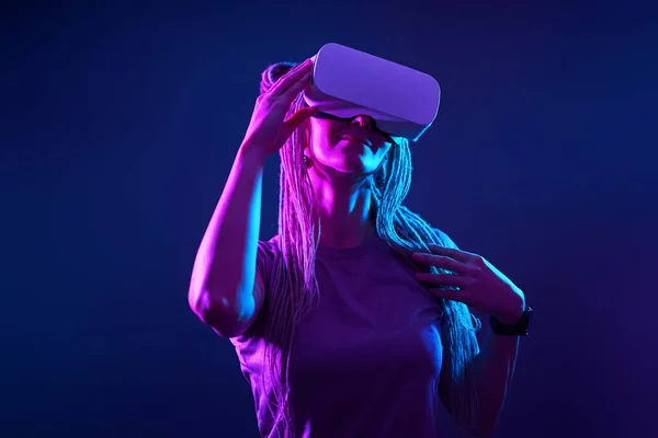 Kobieta używa gogli wirtualnej rzeczywistości. Neon światło studio portret. — Zdjęcie stockowe