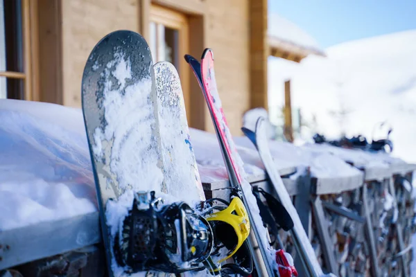 Imagem de esquis multicoloridos e snowboards na neve no resort de inverno à tarde . — Fotografia de Stock
