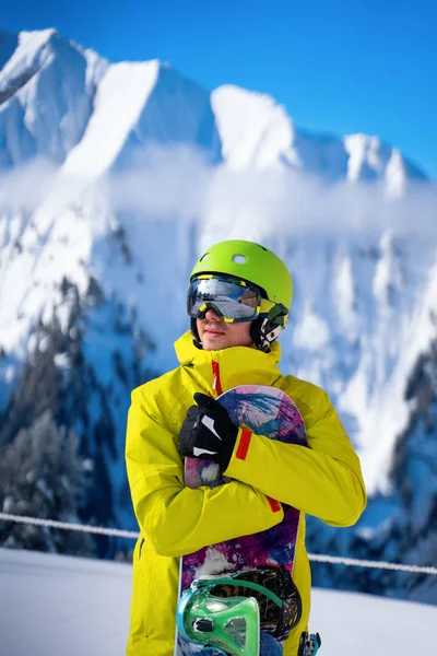 Foto av sportig man med snowboard mot bakgrund av berg — Stockfoto