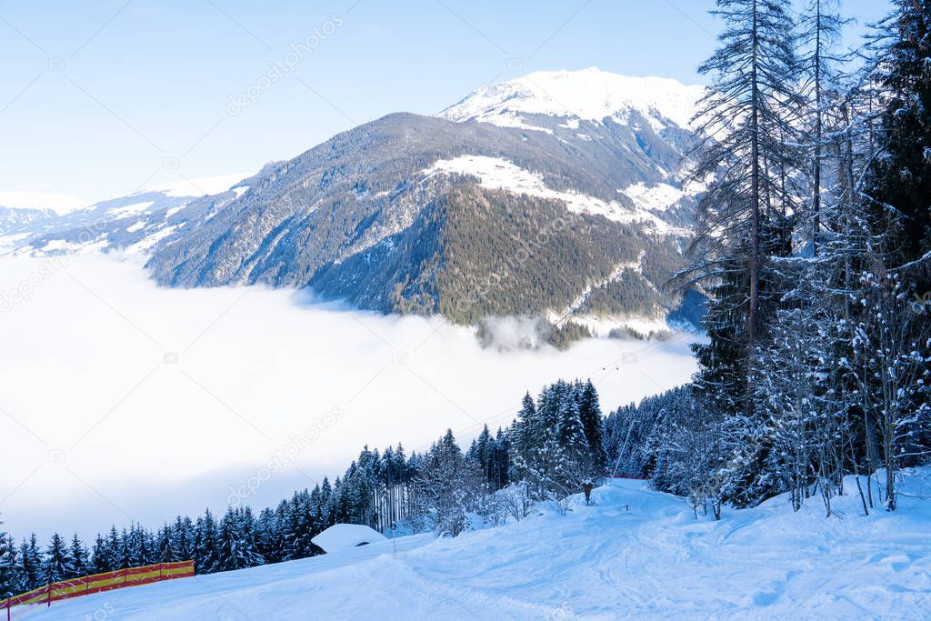 Photo of picturesque highlands with snow mountains, fir trees, blue sky and fog