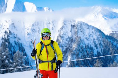 Dağların arka planında kayak yapan kasklı sporcu portresi.
